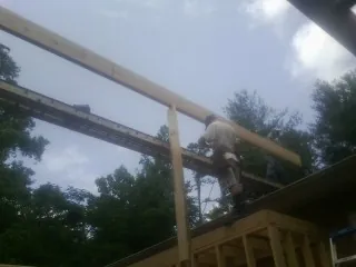 Carpenter setting a ridge beam over a new addition frame — Ice Dam Removal by Roofing Brothers in Westgate