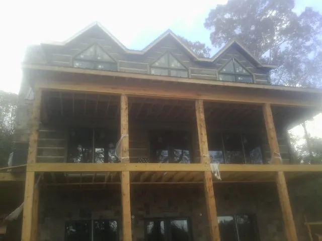 Dormers and porch framing on a large log home under construction — Roof Coating work by our crew in Westgate