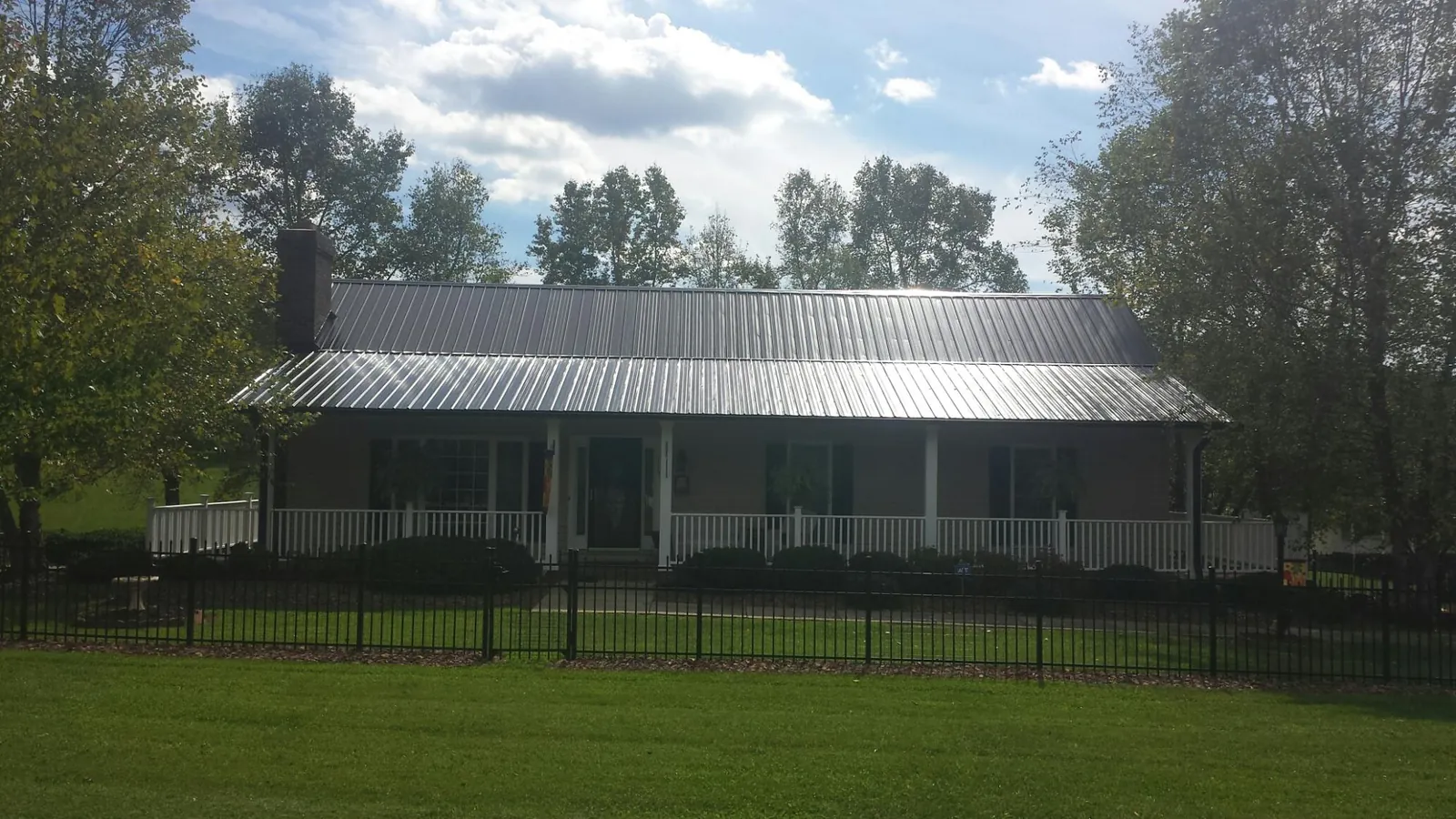 Gray metal roof on a brick ranch with a full width front porch — Gutter Guard Installation work by our crew in Westgate