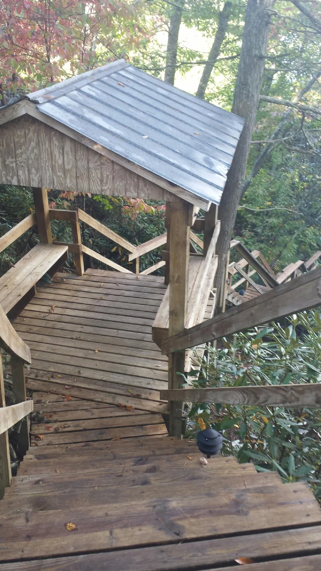 Metal roofed shelter over wooden steps on a wooded walkway — Skylight Repair & Installation work by our crew in Westgate